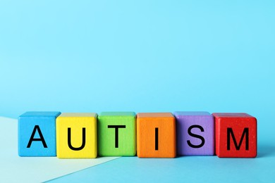 Photo of Word Autism made of colorful cubes on light blue background, space for text