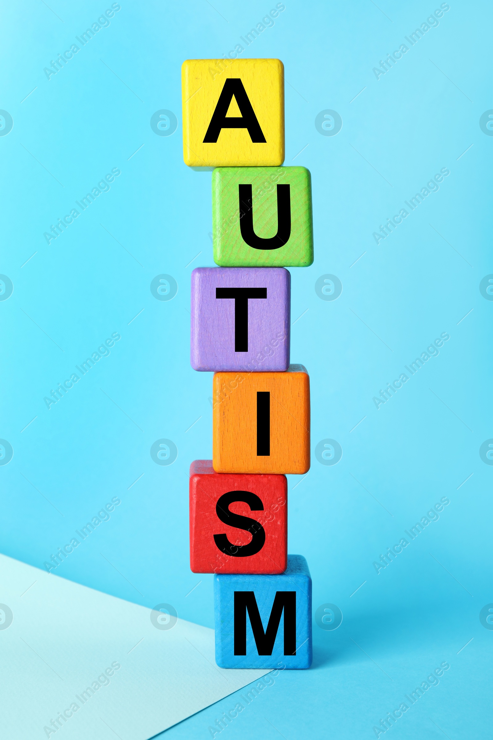 Photo of Word Autism made of colorful cubes on light blue background