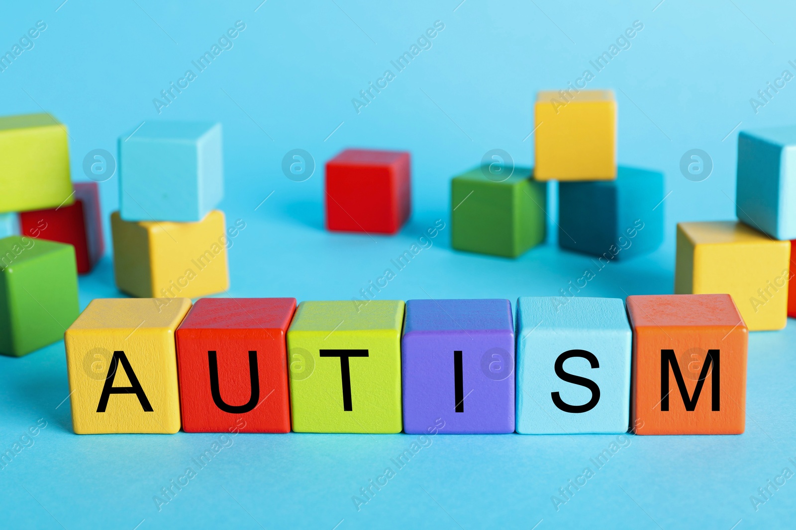 Photo of Word Autism made of colorful cubes on light blue background