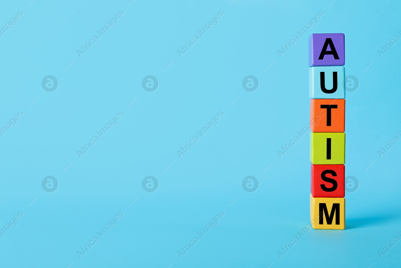 Photo of Word Autism made of colorful cubes on light blue background, space for text