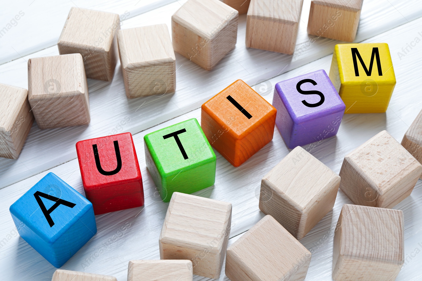 Photo of Word Autism made of colorful cubes on white wooden background