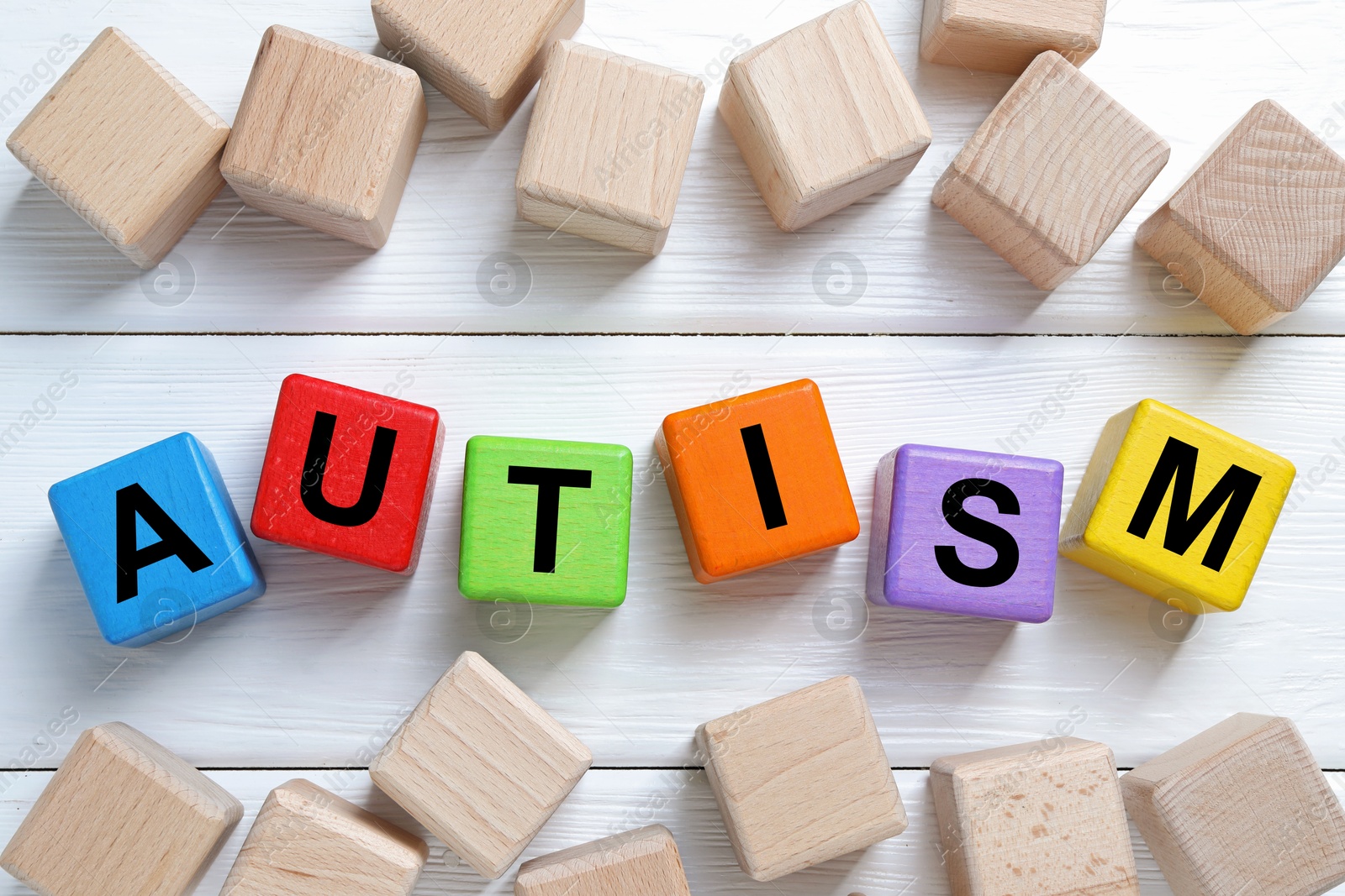 Photo of Word Autism made of colorful cubes on white wooden background, top view