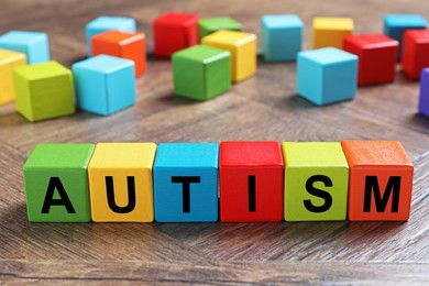 Photo of Word Autism made of colorful cubes on wooden background