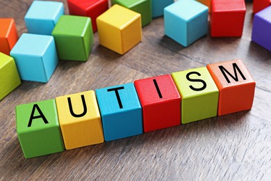 Photo of Word Autism made of colorful cubes on wooden background