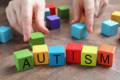 Photo of Autism concept. Woman with colorful cubes at wooden table, closeup