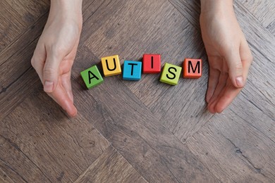 Photo of Autism concept. Woman with colorful cubes at wooden table, top view