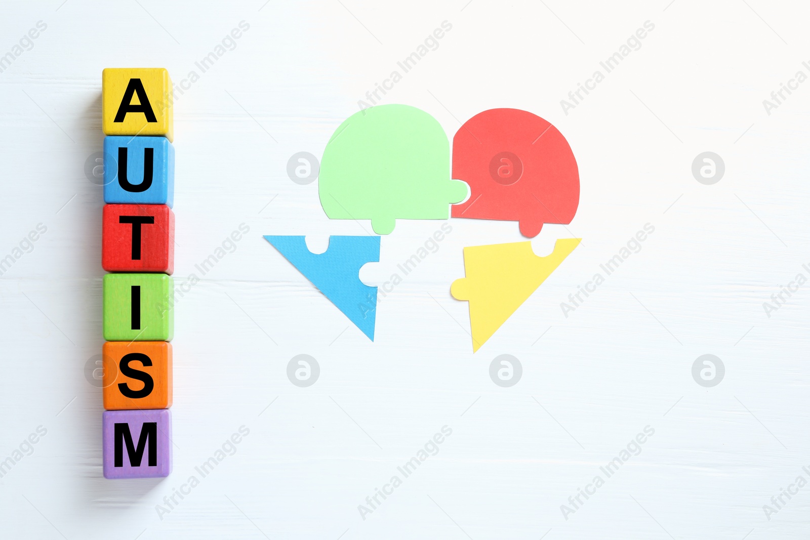 Photo of Word Autism made of colorful cubes and puzzle on white wooden background, flat lay