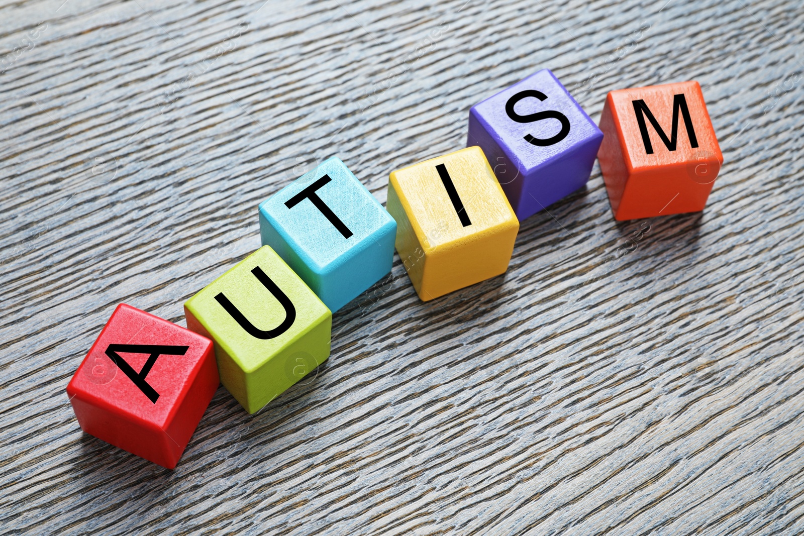 Photo of Word Autism made of colorful cubes on wooden background