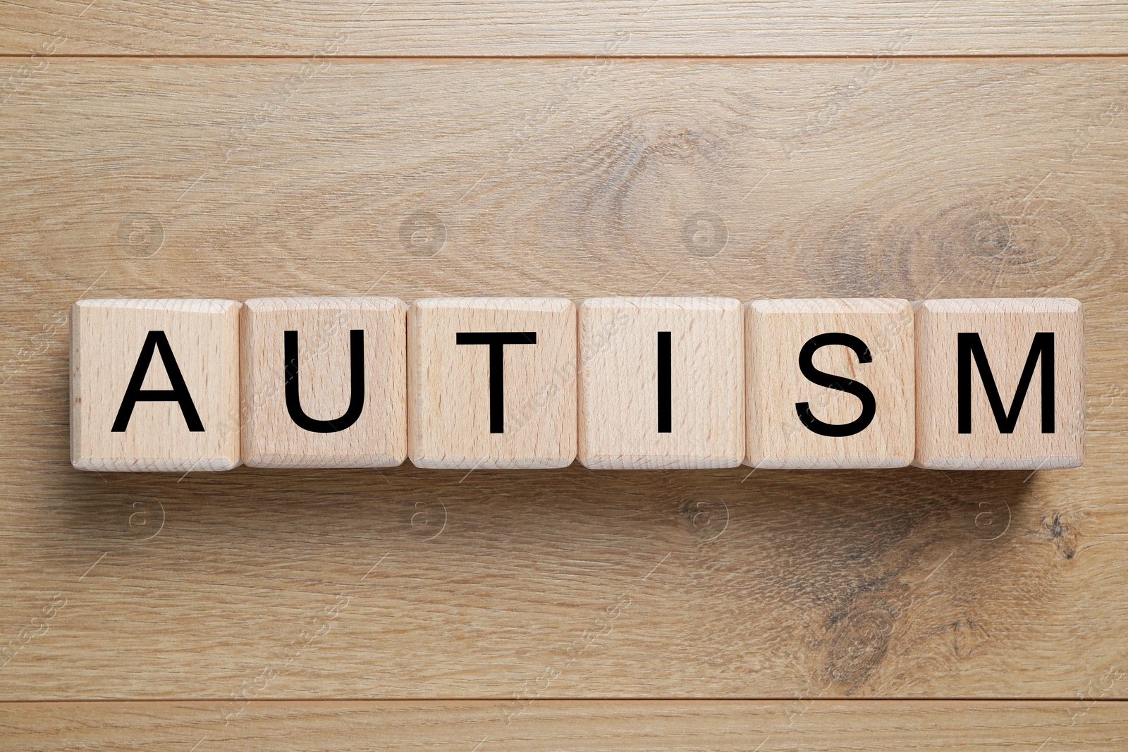 Photo of Word Autism made of cubes on wooden background, top view