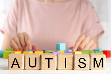 Photo of Autism concept. Woman with colorful cubes at wooden table, selective focus