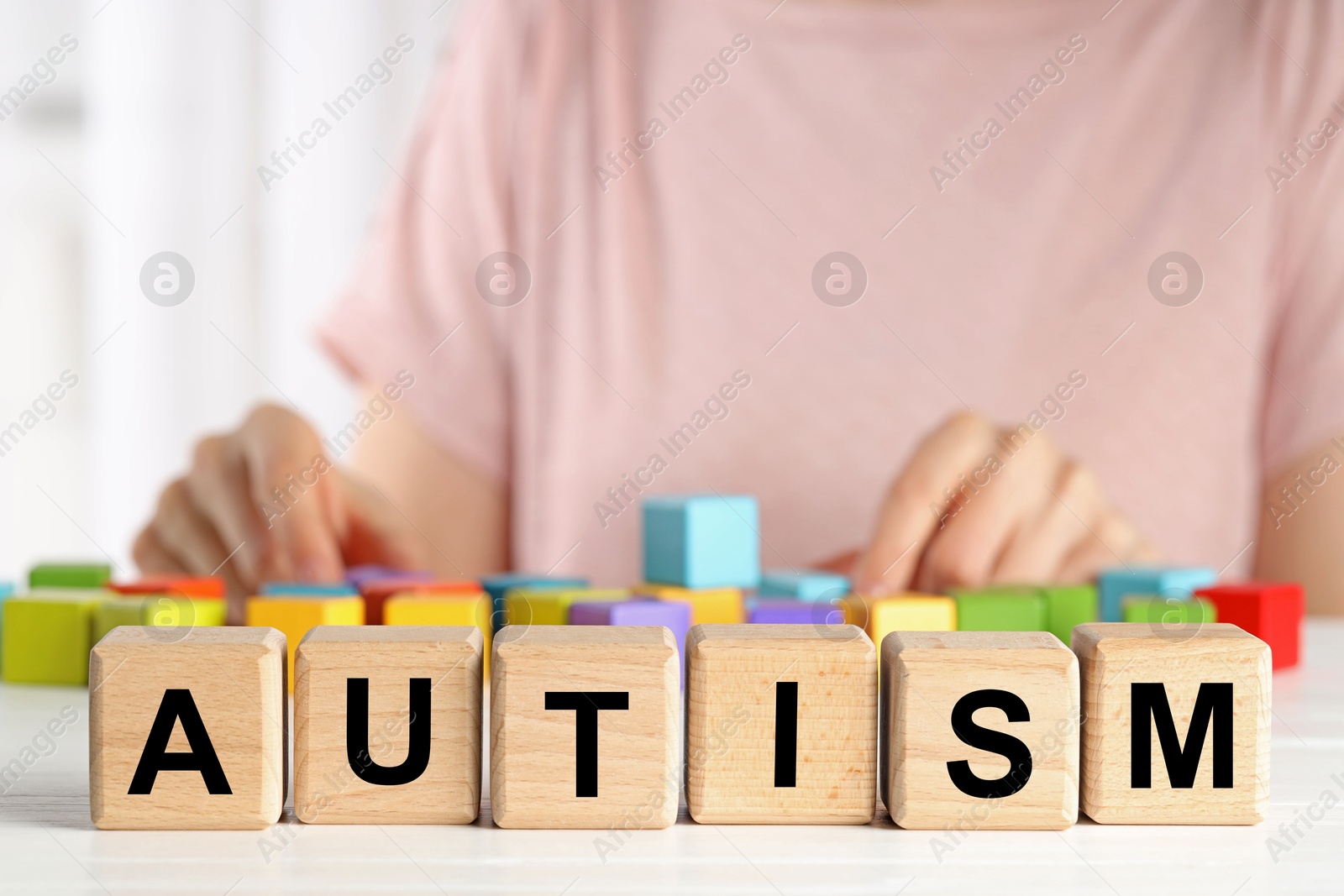 Photo of Autism concept. Woman with colorful cubes at wooden table, selective focus