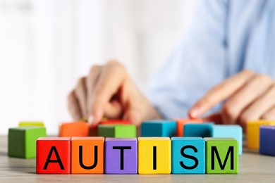 Photo of Autism concept. Woman with colorful cubes at wooden table, selective focus