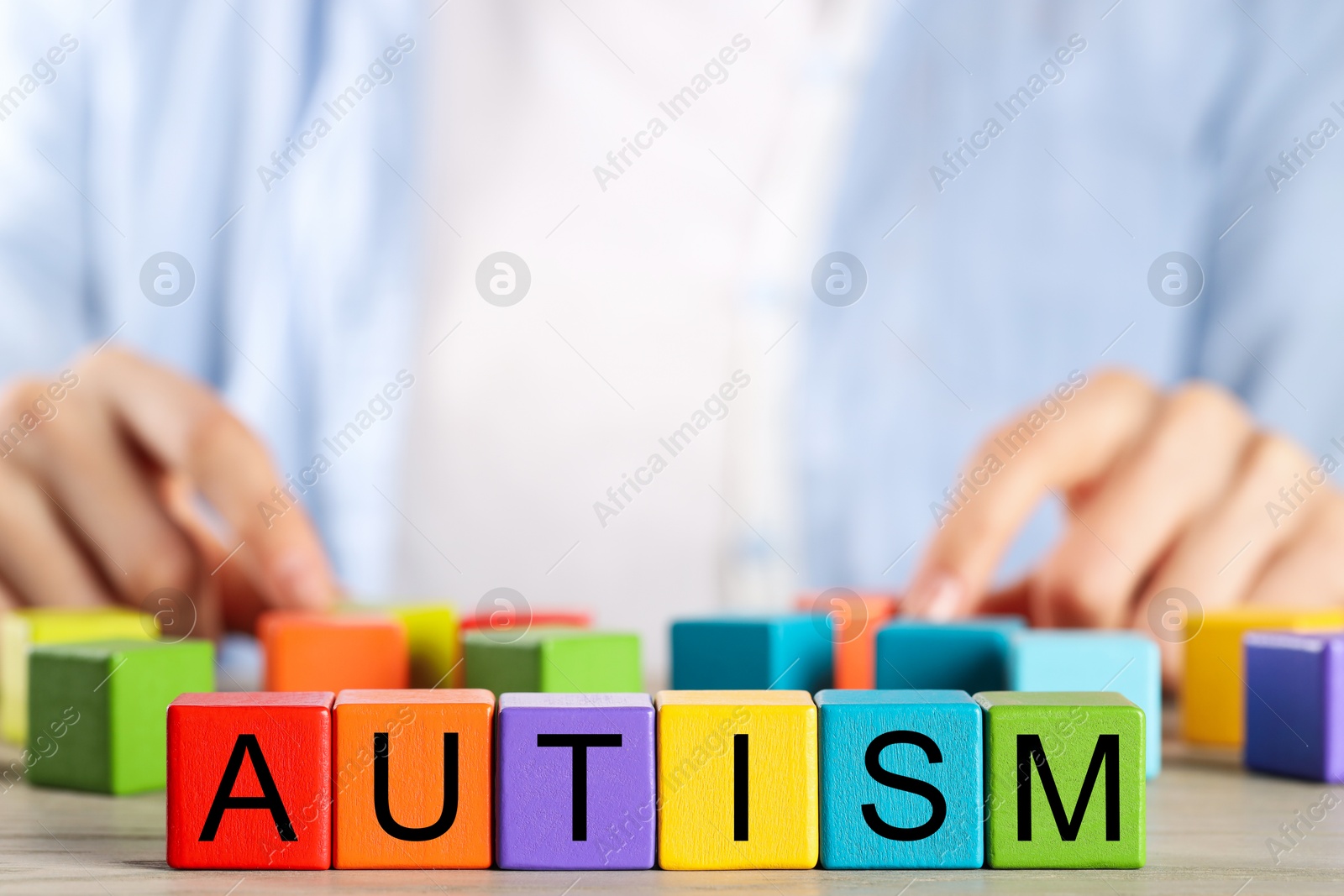 Photo of Autism concept. Woman with colorful cubes at wooden table, selective focus