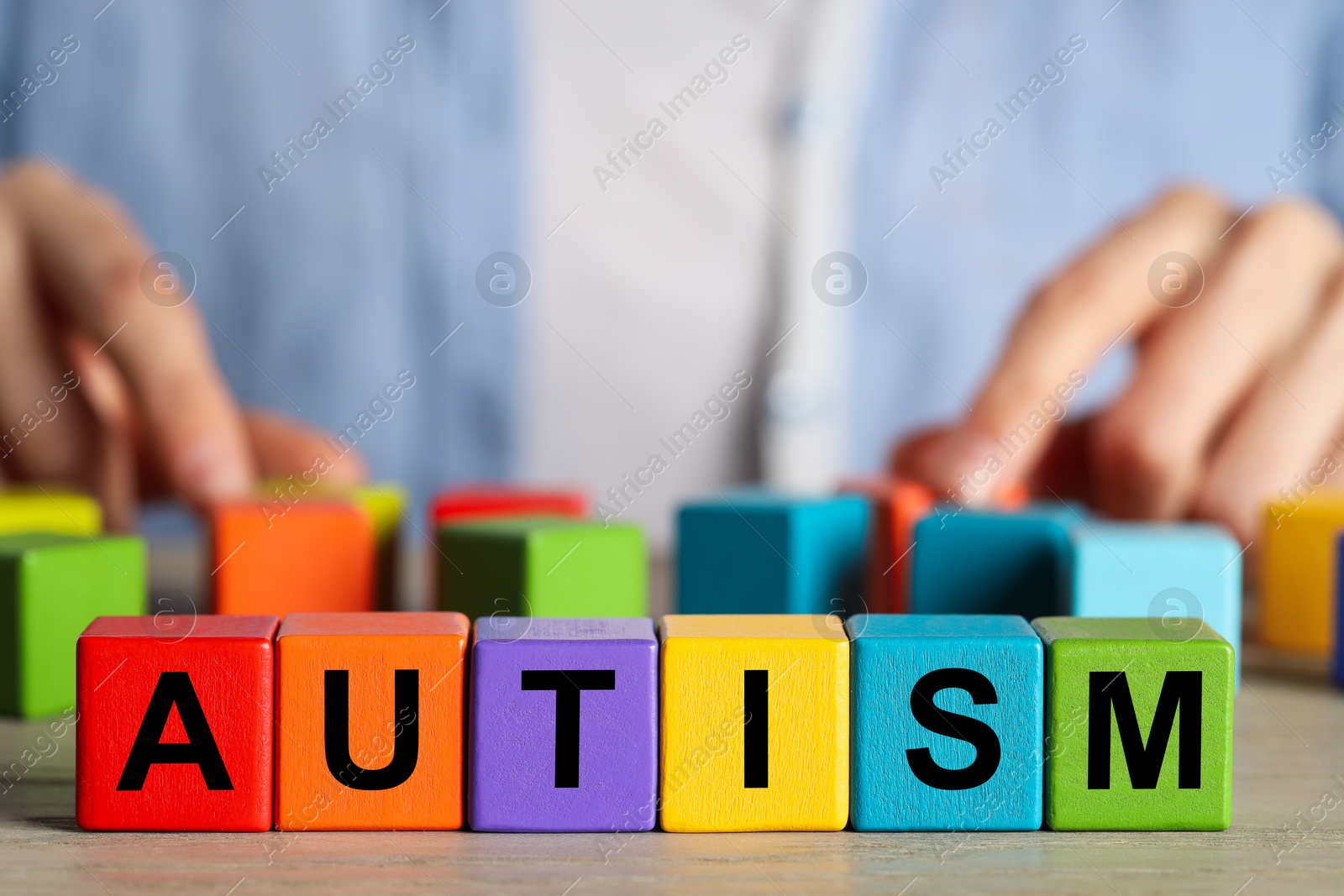 Photo of Autism concept. Woman with colorful cubes at wooden table, selective focus