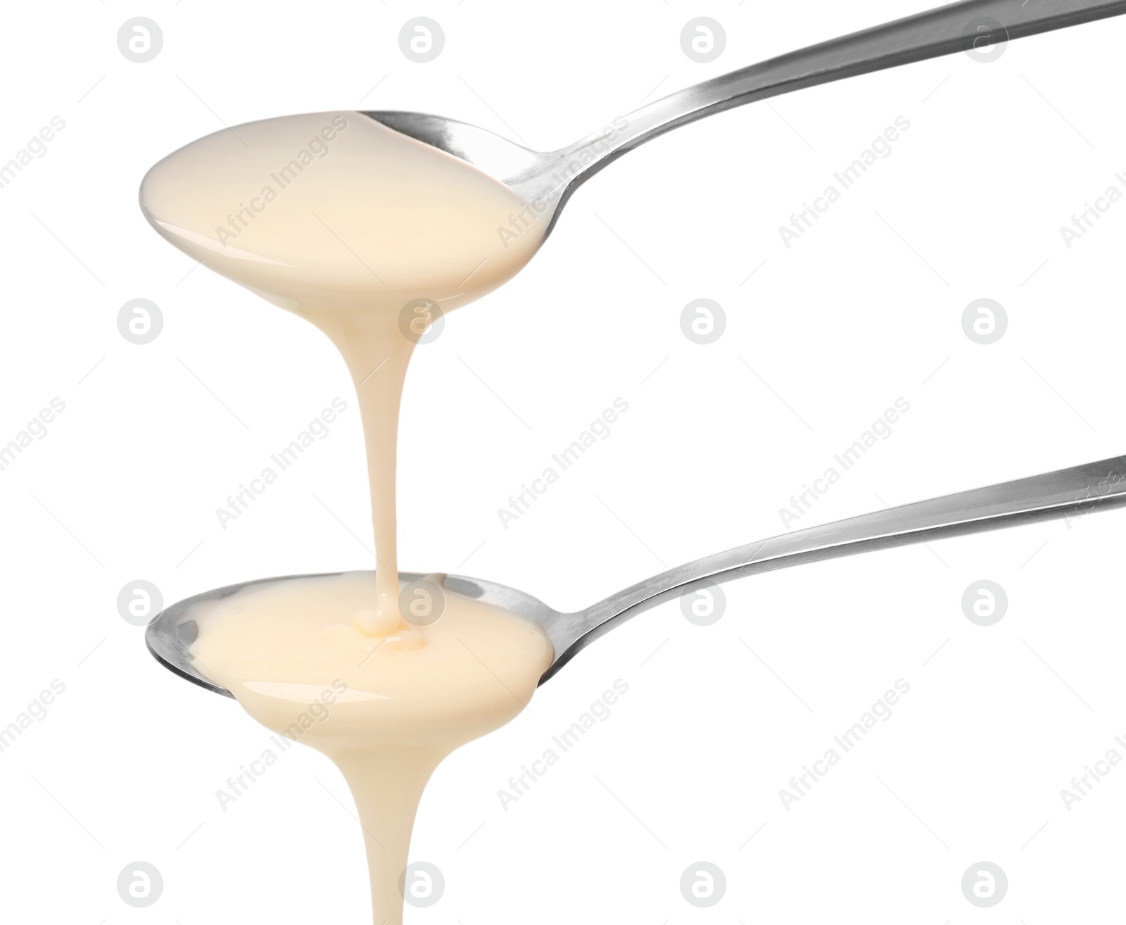 Photo of Condensed milk flowing down from spoons isolated on white