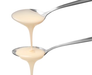 Photo of Condensed milk flowing down from spoons isolated on white