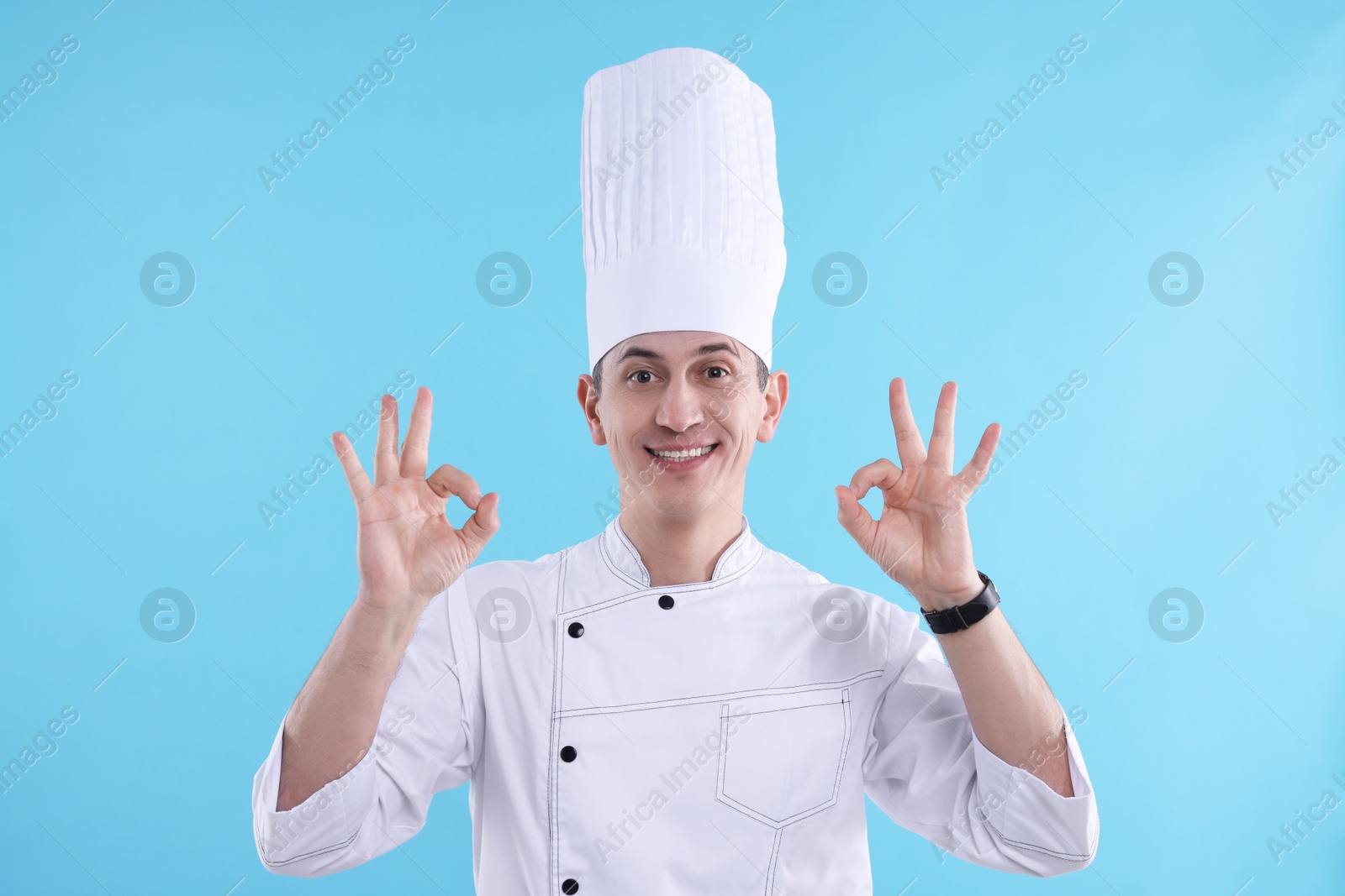 Photo of Professional chef showing okay gesture on light blue background