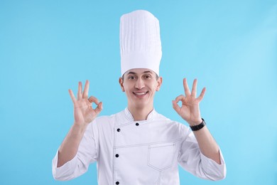 Photo of Professional chef showing okay gesture on light blue background