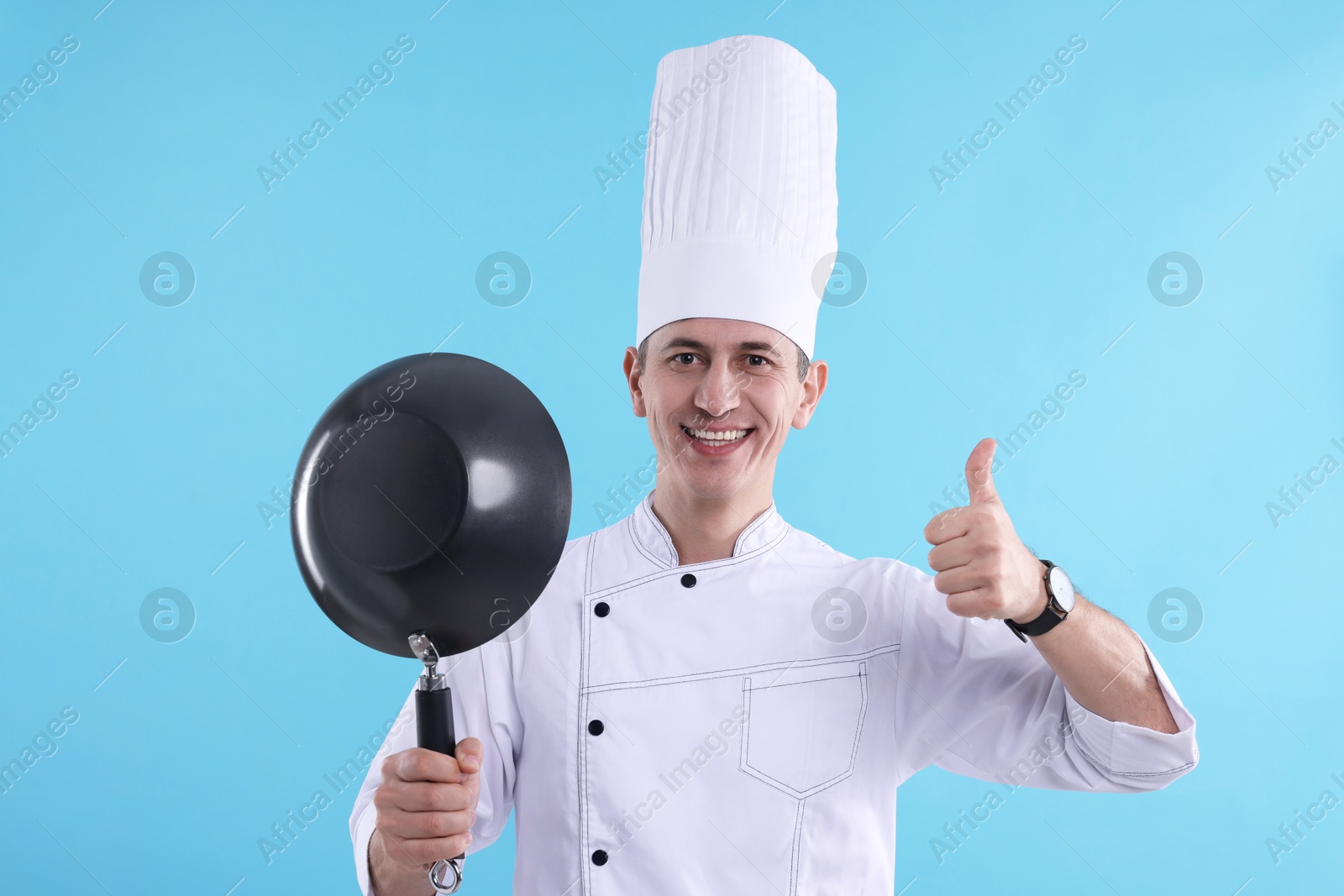 Photo of Professional chef with wok showing thumbs up on light blue background