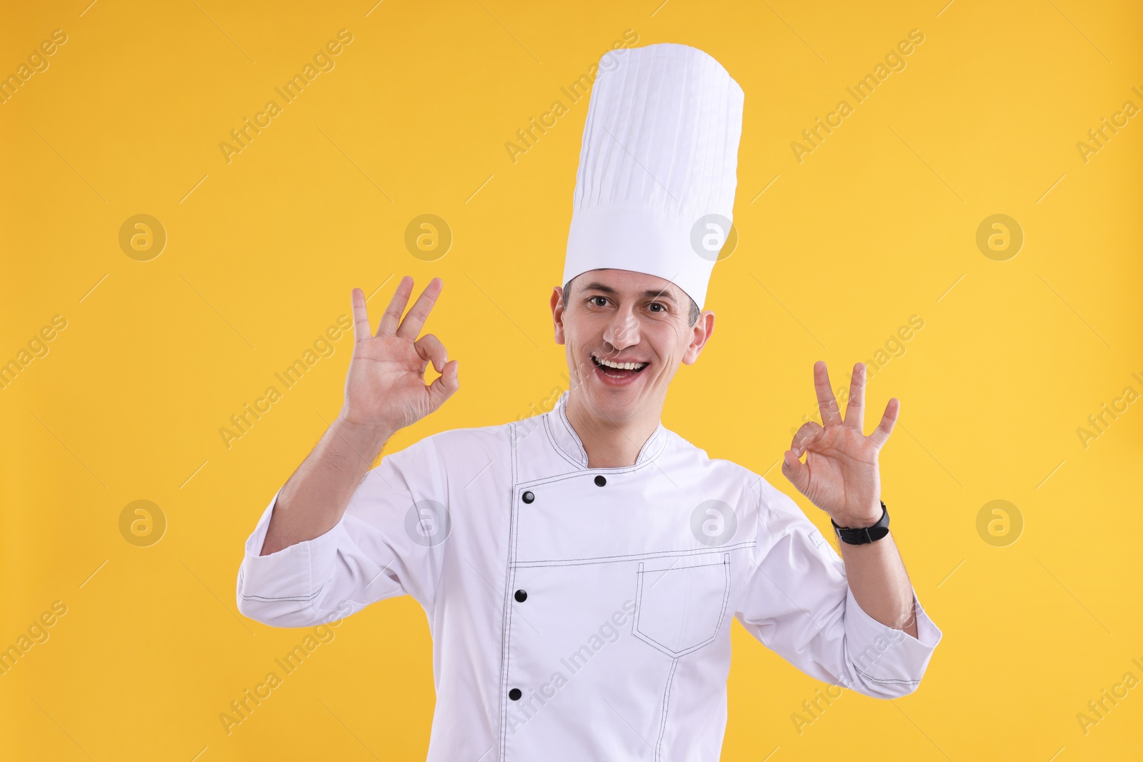 Photo of Professional chef showing okay gesture on orange background