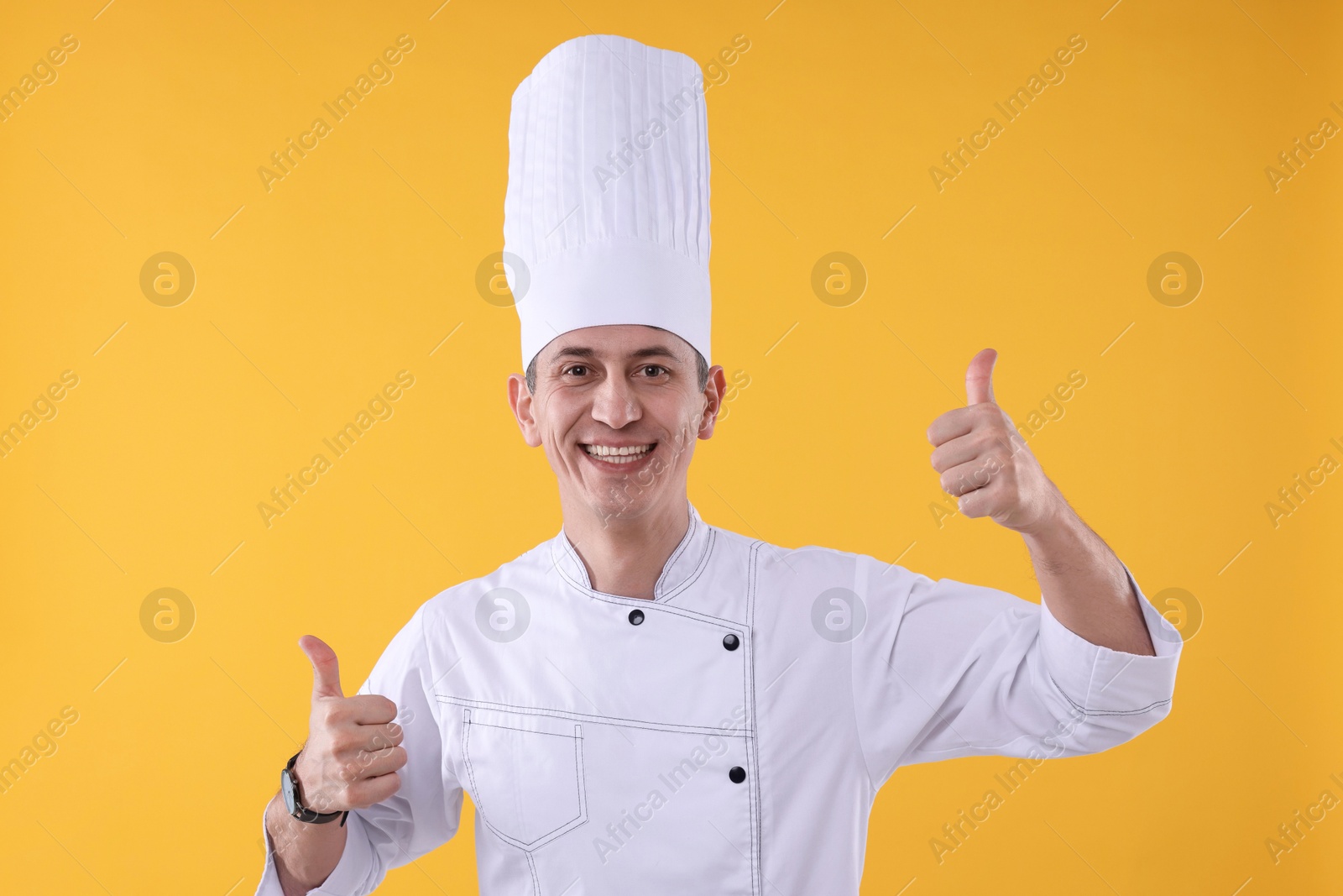 Photo of Professional chef showing thumbs up on orange background