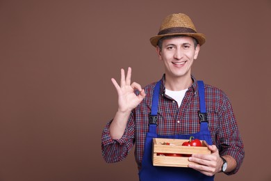 Photo of Farmer with vegetables showing okay gesture on brown background. Space for text