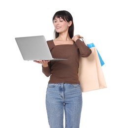 Photo of Internet shopping. Happy woman with laptop and colorful bags on white background