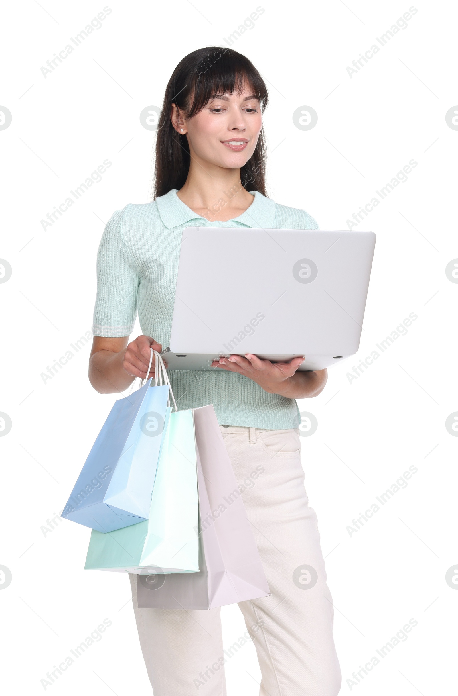 Photo of Internet shopping. Happy woman with laptop and colorful bags on white background