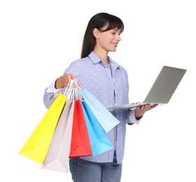 Photo of Internet shopping. Smiling woman with laptop and colorful bags on white background