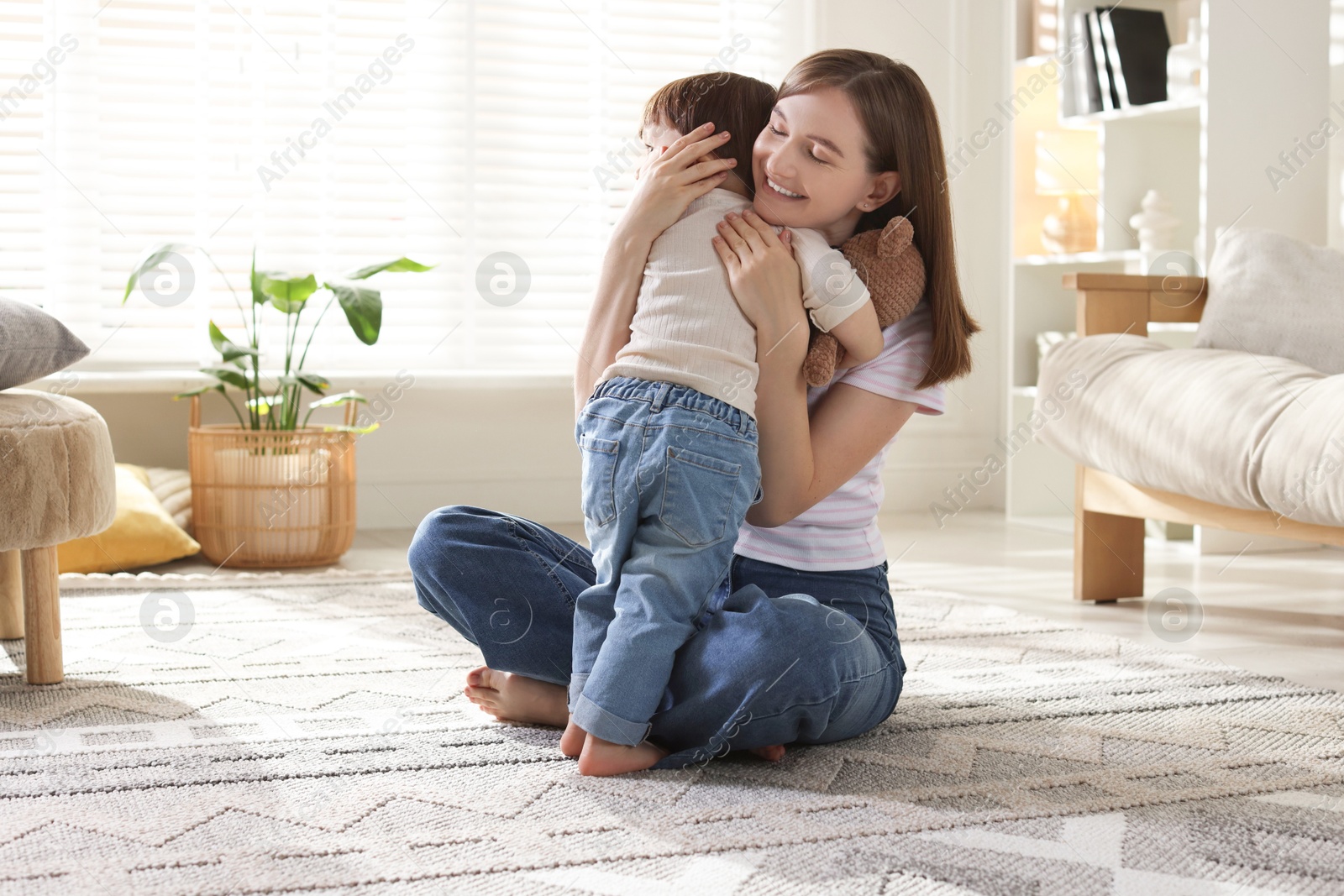 Photo of Happy mother with her cute little son on carpet at home