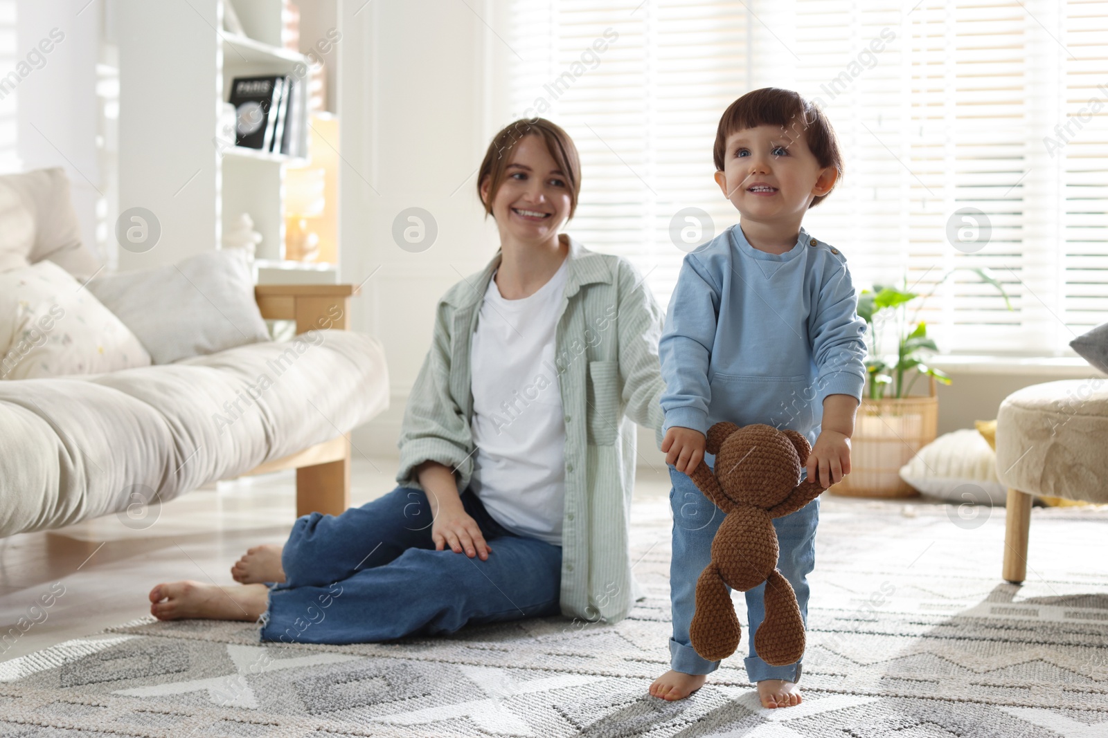 Photo of Happy mother and her cute little son with toy bear at home