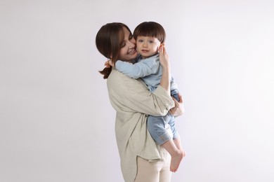 Photo of Beautiful mother with her cute little son on light grey background