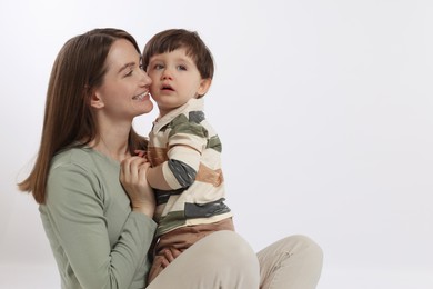 Photo of Happy mother with her cute little son on white background, space for text