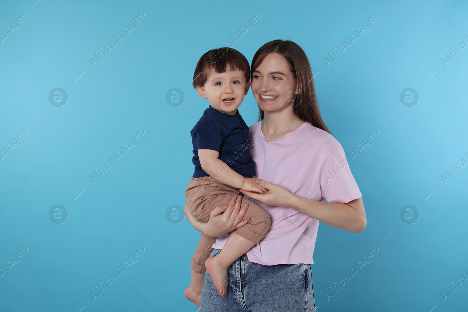 Photo of Happy mother with her cute little son on light blue background