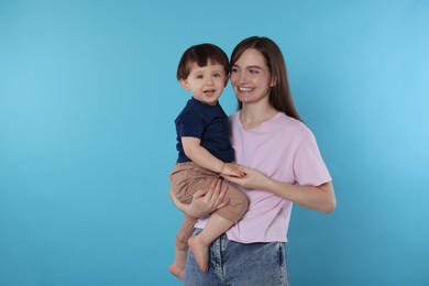 Photo of Happy mother with her cute little son on light blue background