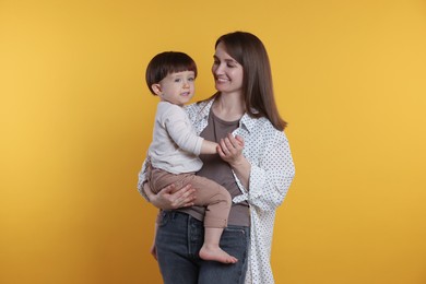 Photo of Happy mother with her cute little son on yellow background