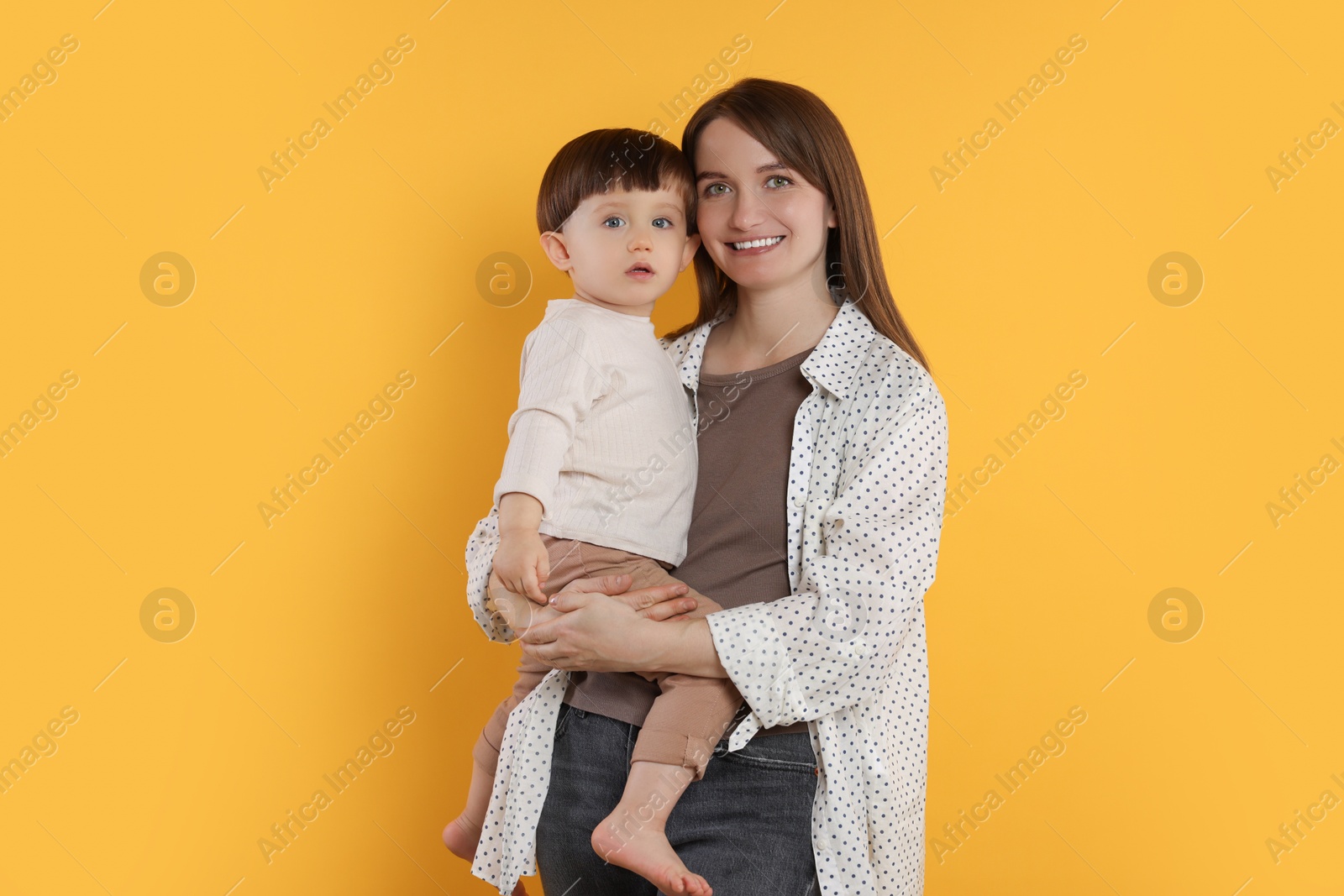 Photo of Happy mother with her cute little son on yellow background