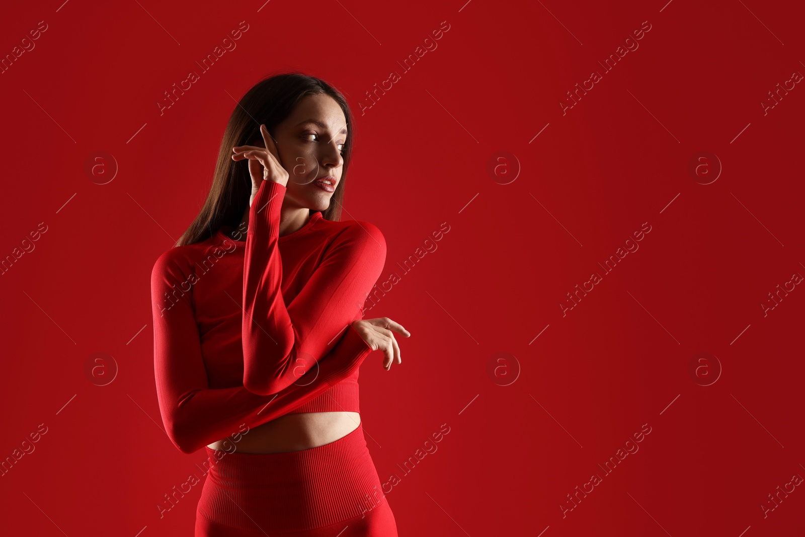 Photo of Beautiful woman in stylish sportswear on red background. Space for text