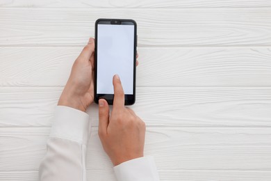 Photo of Woman unlocking smartphone with fingerprint scanner at white wooden table, top view. Space for text