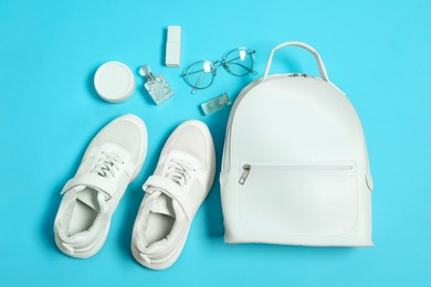 Photo of Stylish sneakers and accessories on light blue background, flat lay