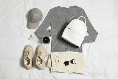 Photo of Stylish outfit with backpack on white fabric, flat lay