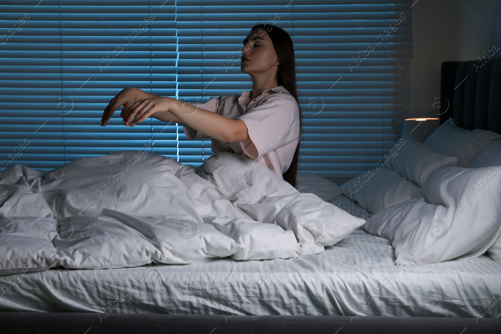 Photo of Young woman suffering from sleepwalking on bed at home