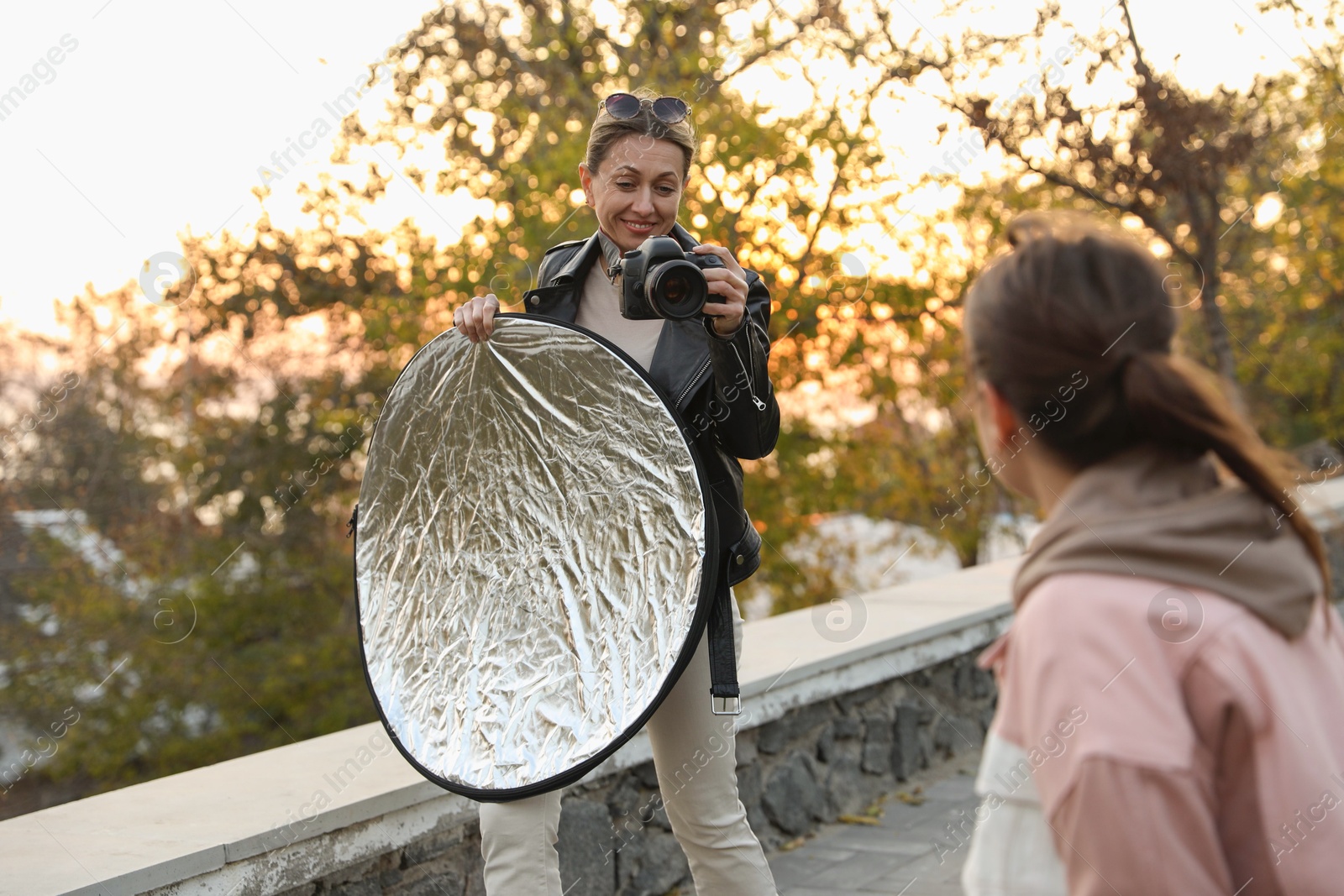 Photo of Professional photographers with reflector and camera outdoors