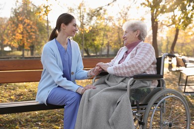 Caregiver with elderly woman in wheelchair at park