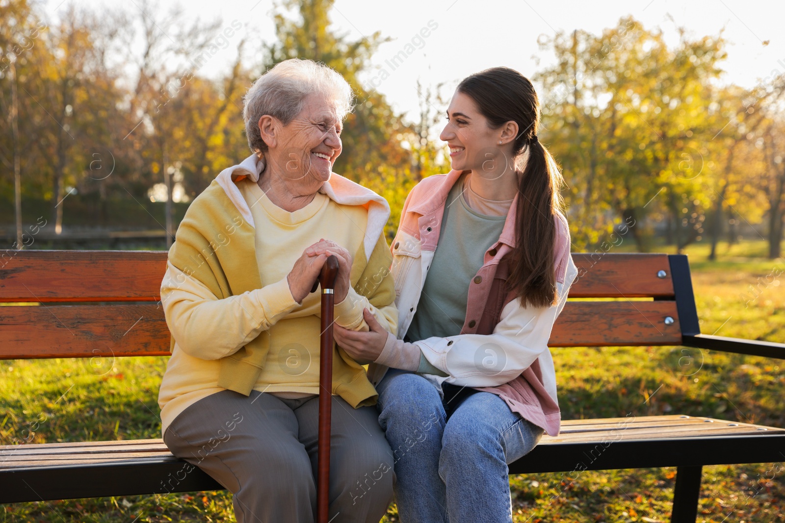 Photo of Elderly woman with walking cane and her caregiver in park