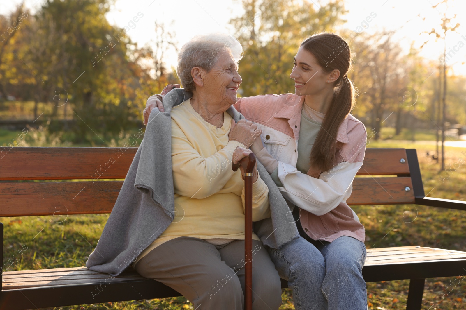 Photo of Elderly woman with walking cane and her caregiver in park