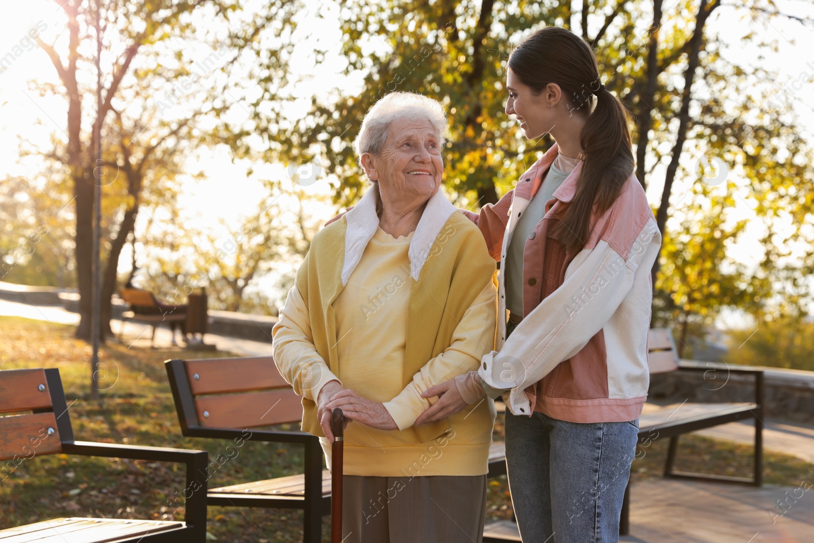 Photo of Elderly woman with walking cane and her caregiver in park