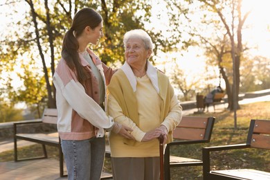 Photo of Elderly woman with walking cane and her caregiver in park