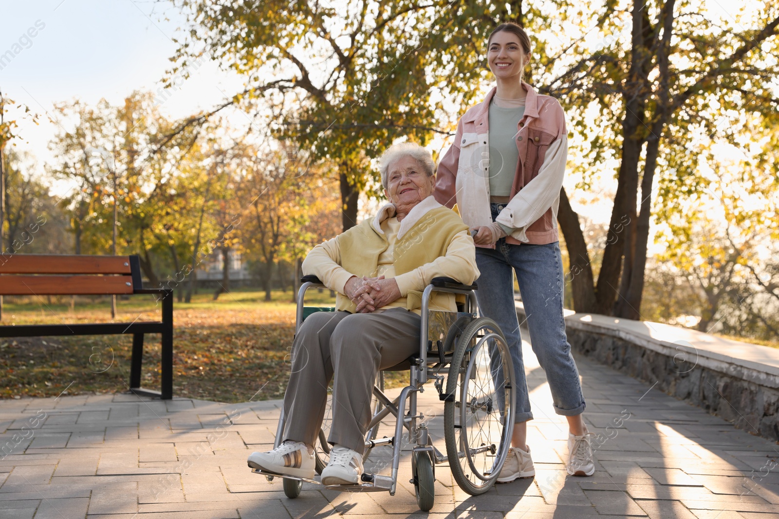 Photo of Caregiver with elderly woman in wheelchair at park