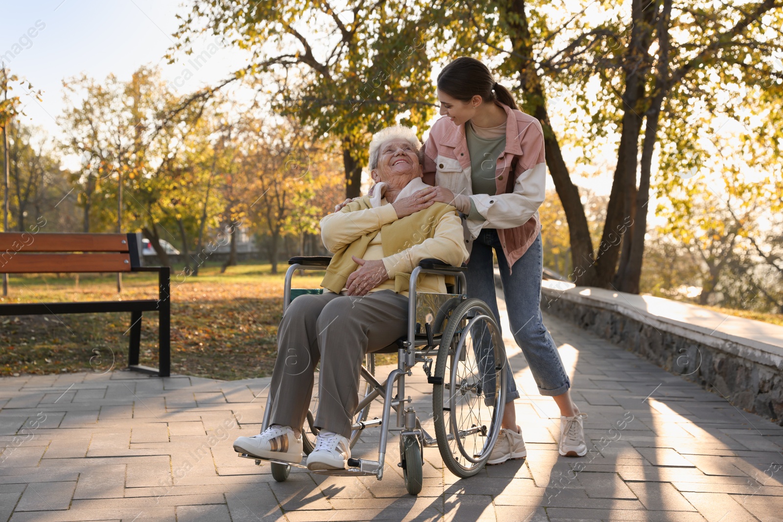 Photo of Caregiver with elderly woman in wheelchair at park